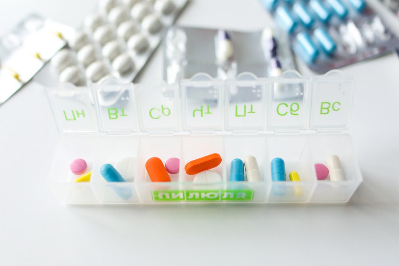 Colorful pills and capsules in a labeled weekly organizer for easy medication management.