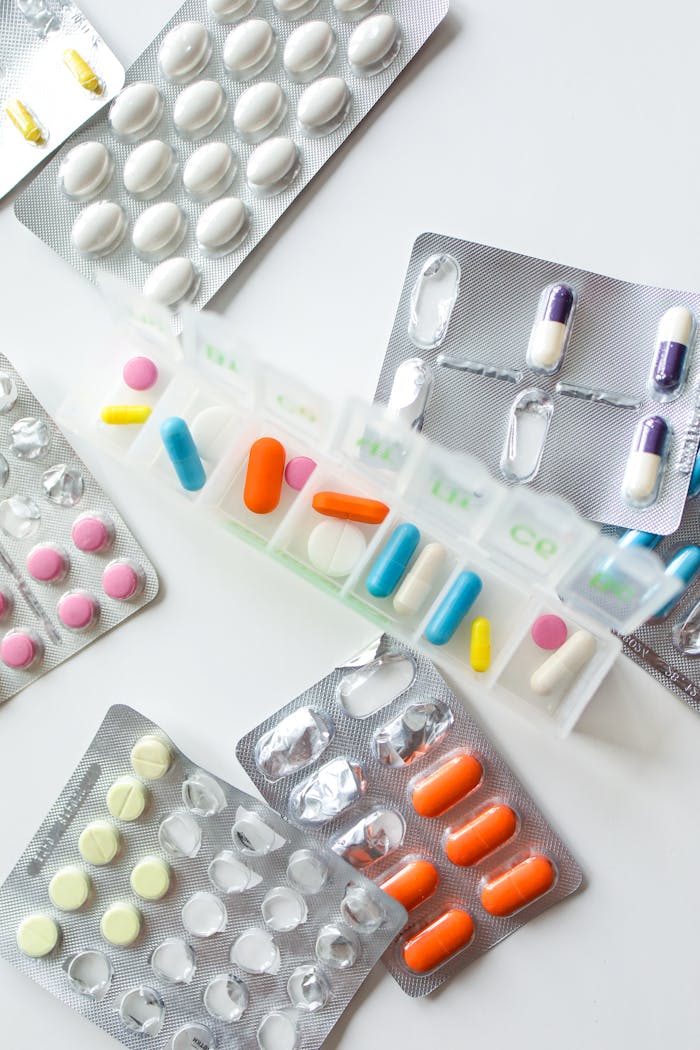 Various pills and capsules organized in blister packs and a weekly organizer on a white background.